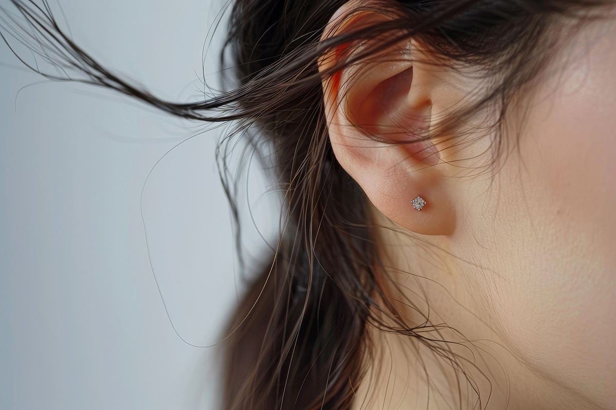 A woman with a black and white photo of her ear with a diamond earring