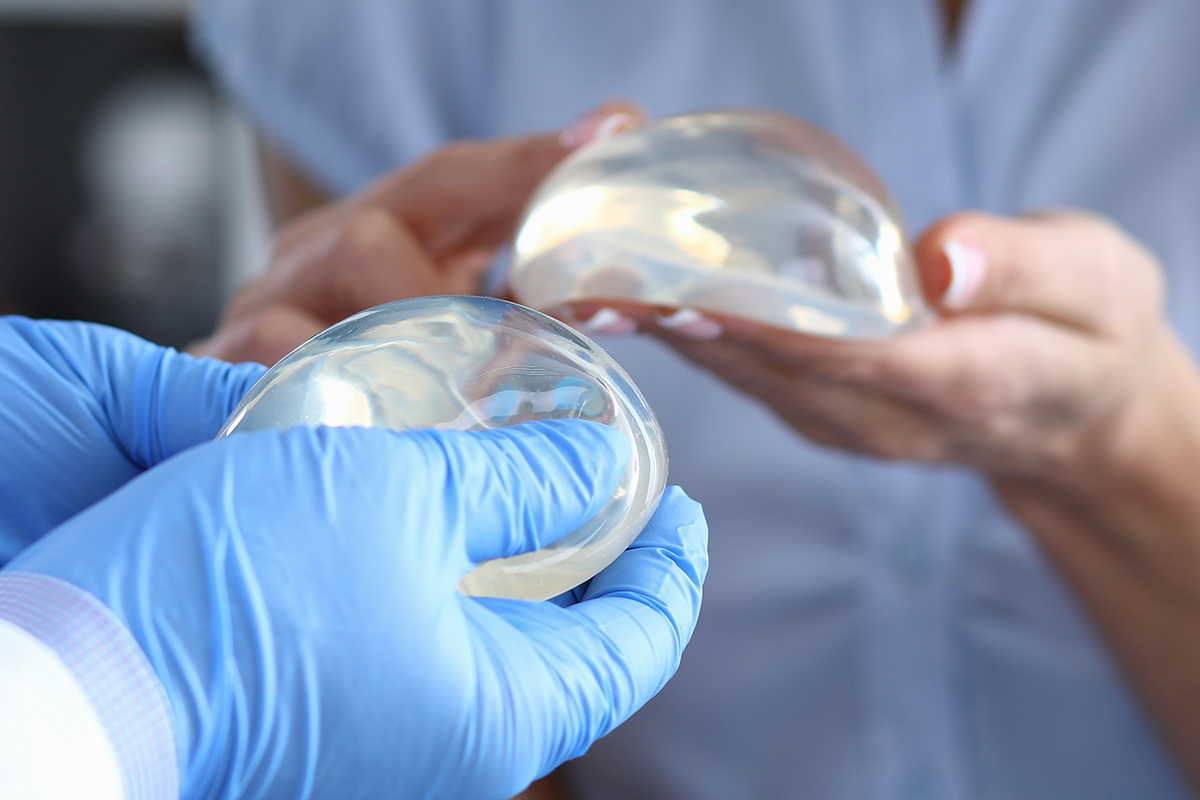 Patient of clinic hold breast implant in his hand and touch it with her finger