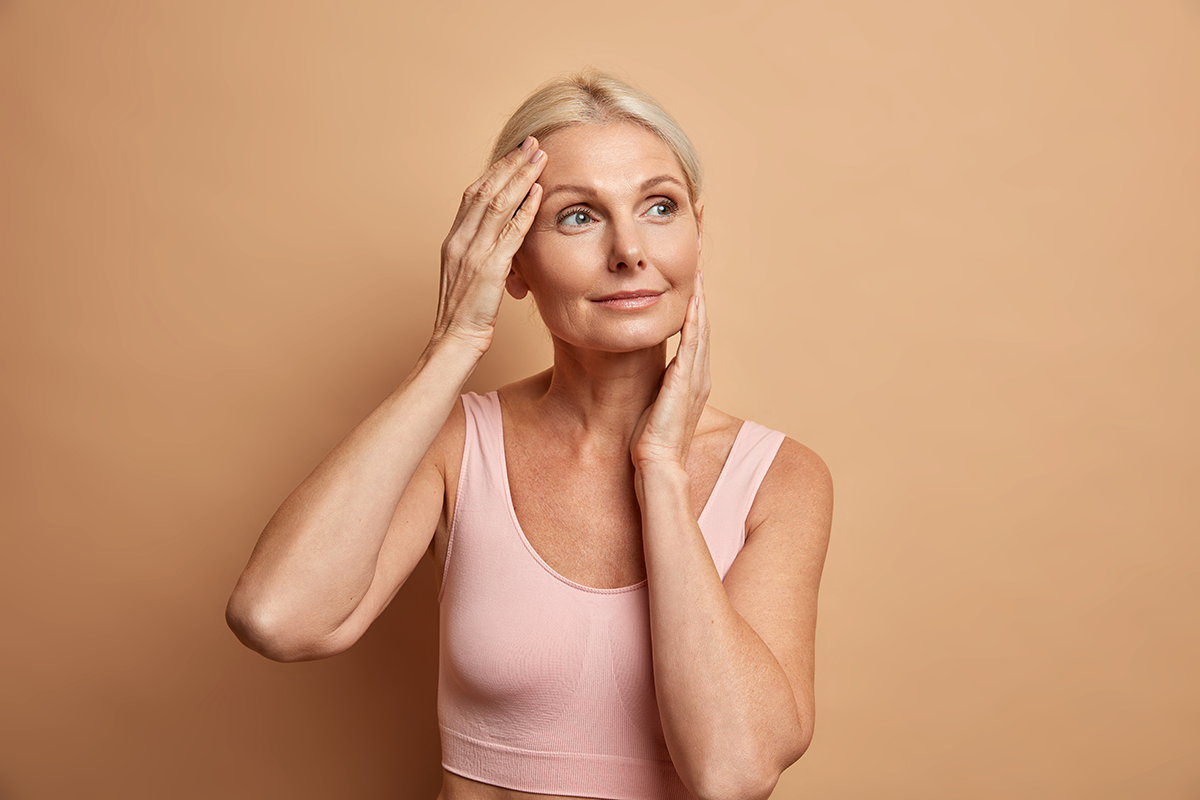 Portrait of mature elderly European woman touches face gently