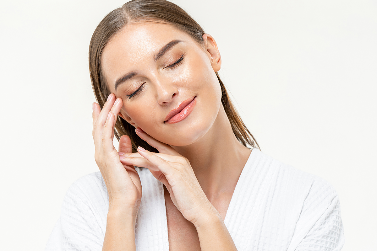 Young beautiful Caucasian woman closing her eyes feeling relaxed with hands touching face